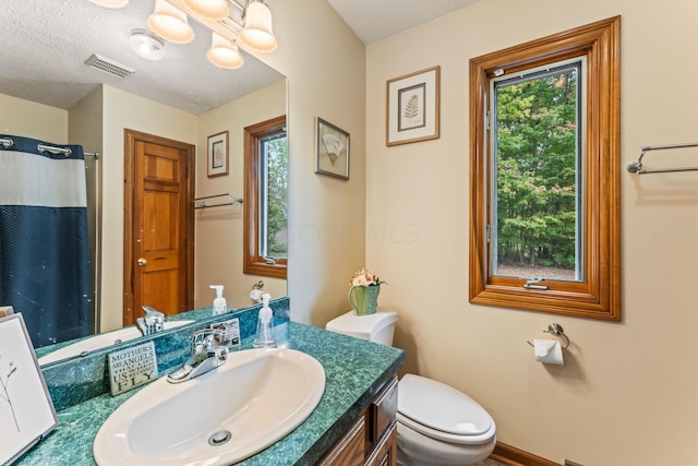 bathroom featuring a healthy amount of sunlight, toilet, and a textured ceiling