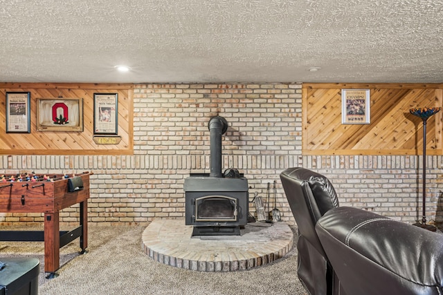 carpeted living room with brick wall, a textured ceiling, a wood stove, and wood walls