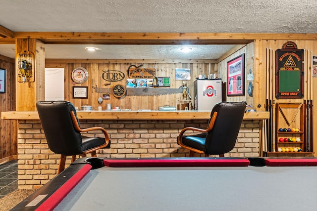 bar featuring a textured ceiling, white refrigerator, wooden walls, and billiards