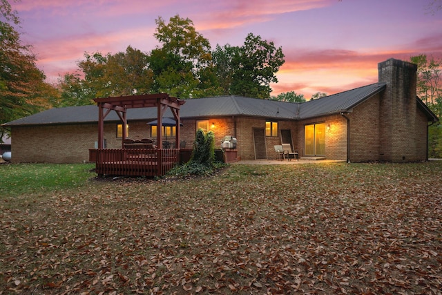 back house at dusk with a patio area, a pergola, a yard, and a deck