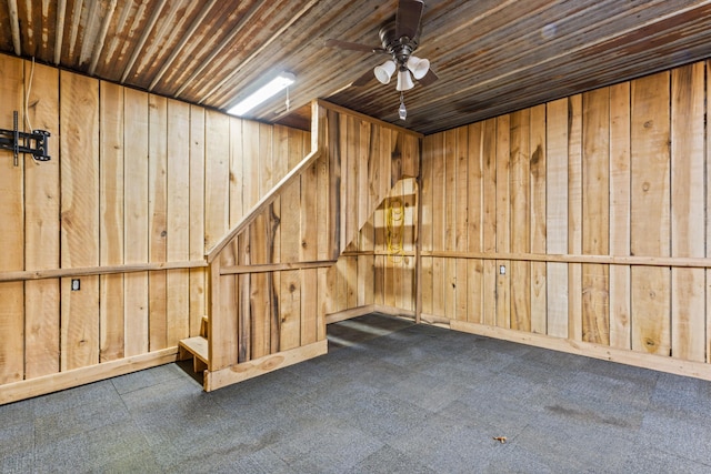 basement with dark colored carpet, wooden ceiling, ceiling fan, and wooden walls