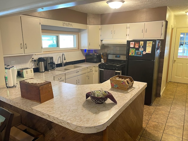 kitchen with black appliances, white cabinets, kitchen peninsula, and sink