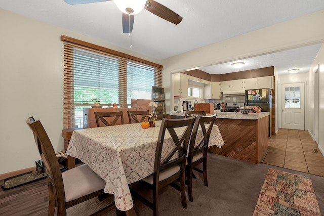 dining space featuring ceiling fan and dark colored carpet