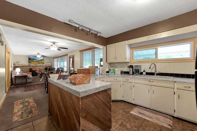 kitchen featuring decorative backsplash, a textured ceiling, dark tile patterned floors, ceiling fan, and sink