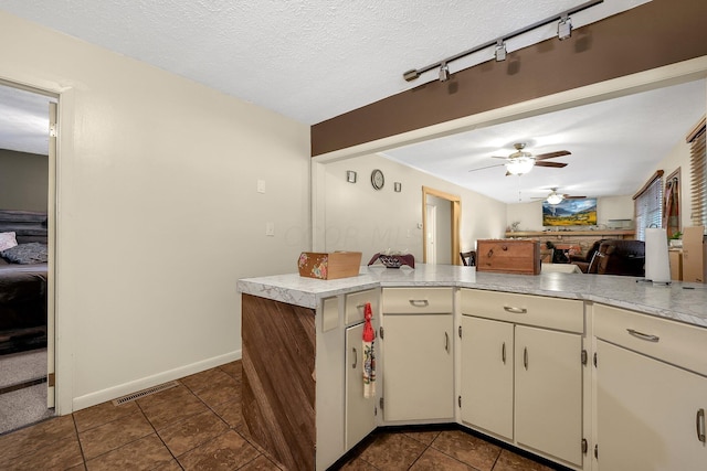 kitchen with kitchen peninsula, a textured ceiling, dark tile patterned floors, and ceiling fan