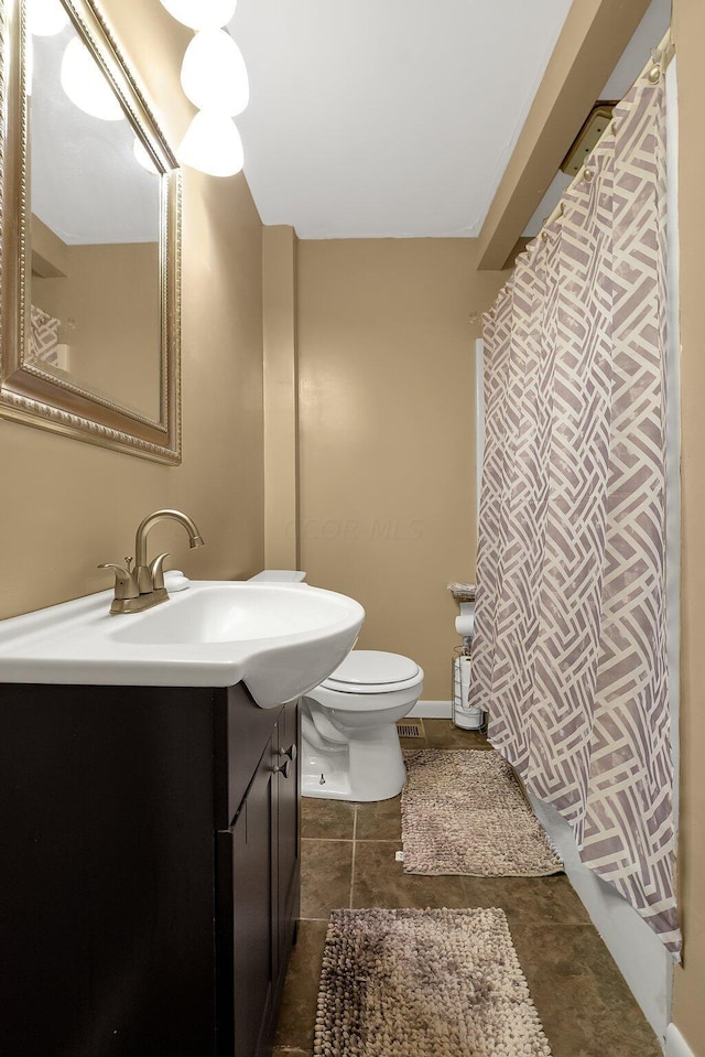 bathroom with tile patterned floors, walk in shower, vanity, and toilet