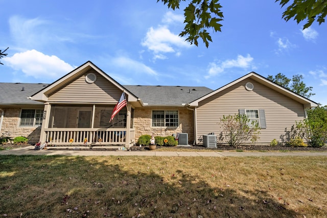 back of property with a sunroom, central AC, and a lawn