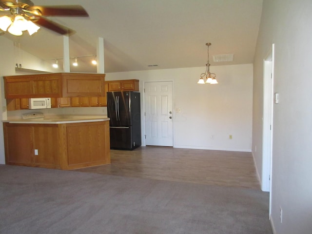 kitchen featuring pendant lighting, ceiling fan with notable chandelier, black fridge, and carpet