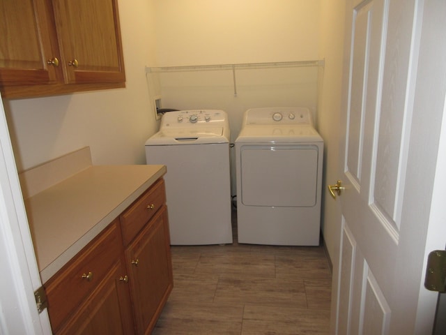 clothes washing area with cabinets and separate washer and dryer