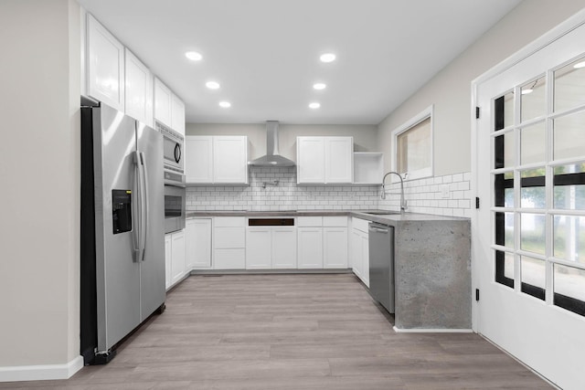 kitchen with sink, a healthy amount of sunlight, wall chimney range hood, and appliances with stainless steel finishes