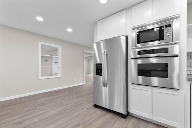 kitchen with white cabinets, appliances with stainless steel finishes, and light wood-type flooring