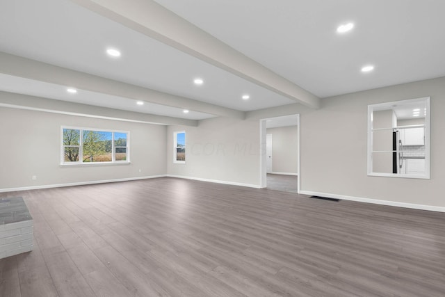 unfurnished living room with beamed ceiling and wood-type flooring