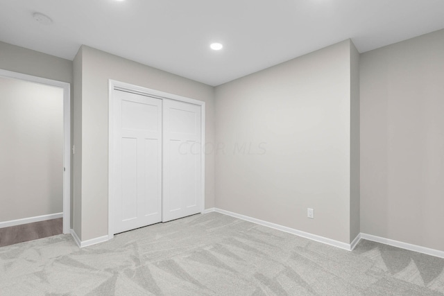 unfurnished bedroom featuring light colored carpet and a closet