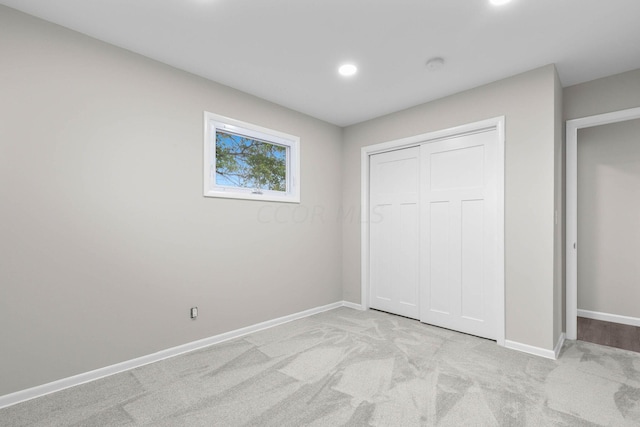 unfurnished bedroom with light carpet and a closet