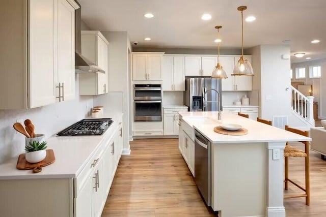 kitchen with light wood-style flooring, appliances with stainless steel finishes, a breakfast bar, and light countertops