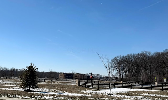 yard covered in snow with a rural view and fence