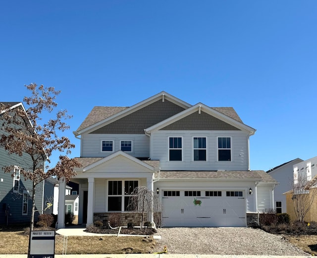 craftsman inspired home featuring gravel driveway, a garage, and stone siding