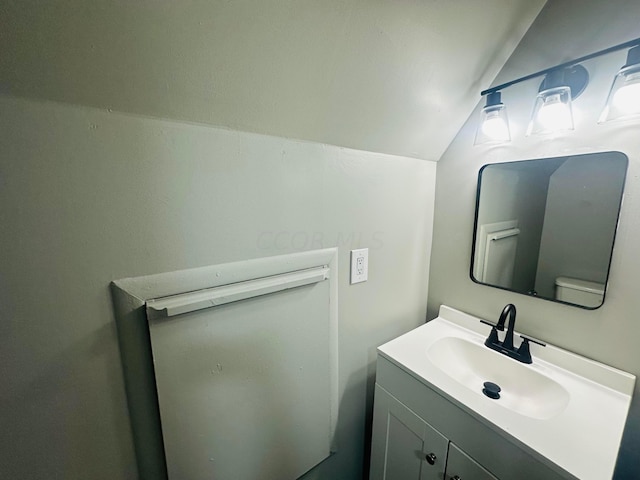 bathroom featuring vanity, toilet, and vaulted ceiling