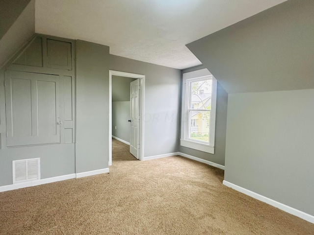 additional living space with light carpet and vaulted ceiling