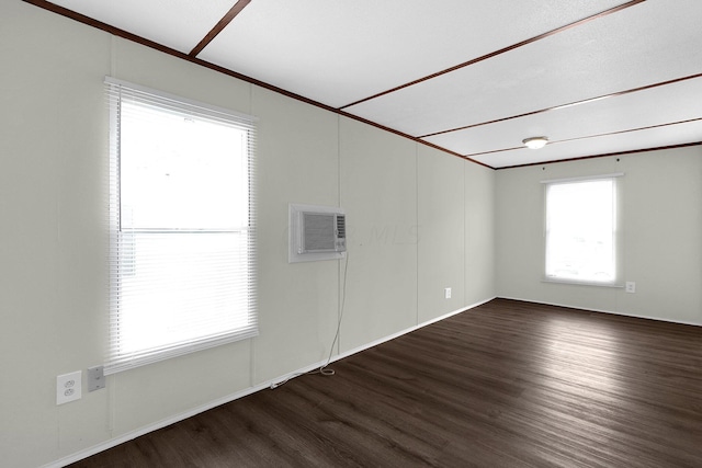 spare room featuring a wealth of natural light, dark wood-type flooring, and a wall mounted air conditioner