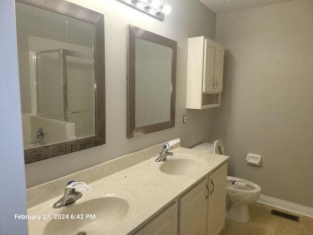 bathroom with tile patterned floors, vanity, toilet, and a shower with door