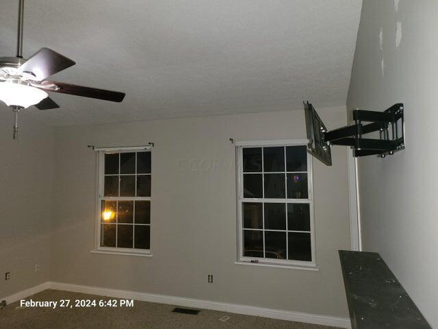 carpeted empty room with ceiling fan and a textured ceiling