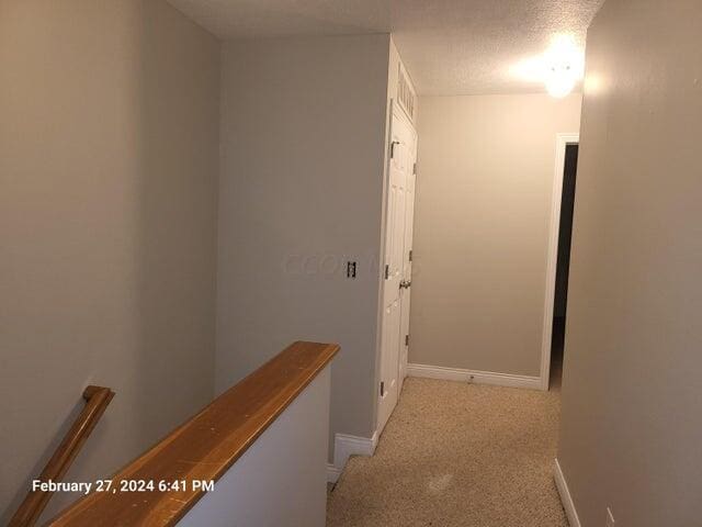 hall with light carpet and a textured ceiling