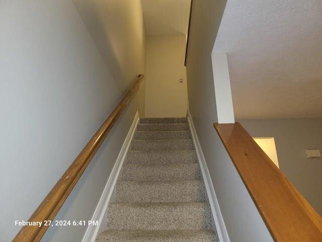 stairs featuring carpet floors and a textured ceiling