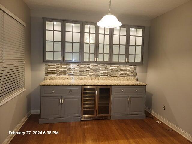 bar featuring decorative backsplash, pendant lighting, beverage cooler, and dark wood-type flooring