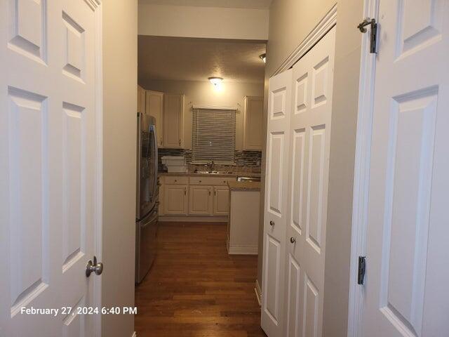 kitchen featuring decorative backsplash, stainless steel fridge, dark hardwood / wood-style flooring, sink, and white cabinetry