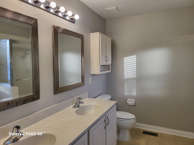 bathroom featuring vanity, a shower with door, tile patterned flooring, toilet, and a textured ceiling