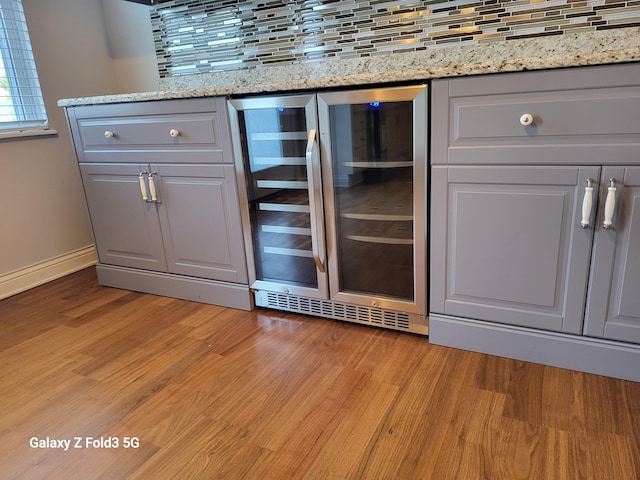 interior space with gray cabinetry, light wood-type flooring, backsplash, and beverage cooler