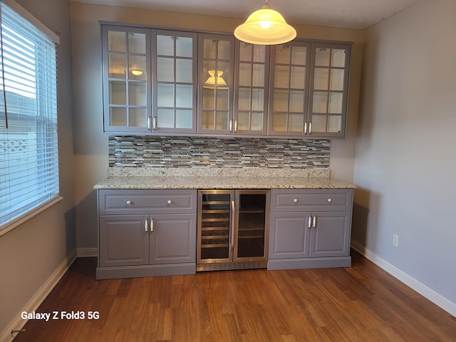 bar featuring tasteful backsplash, decorative light fixtures, beverage cooler, and gray cabinetry