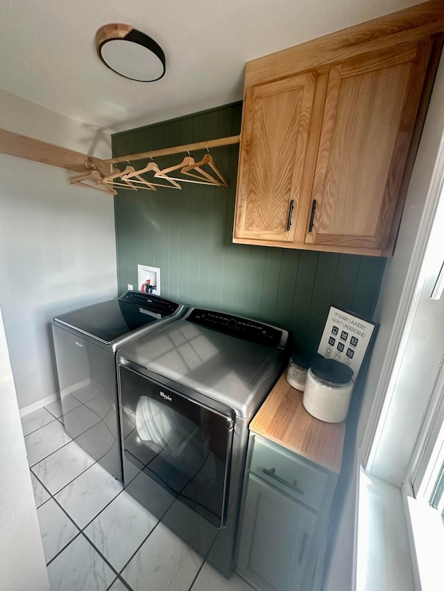 washroom featuring separate washer and dryer, wood walls, and cabinets