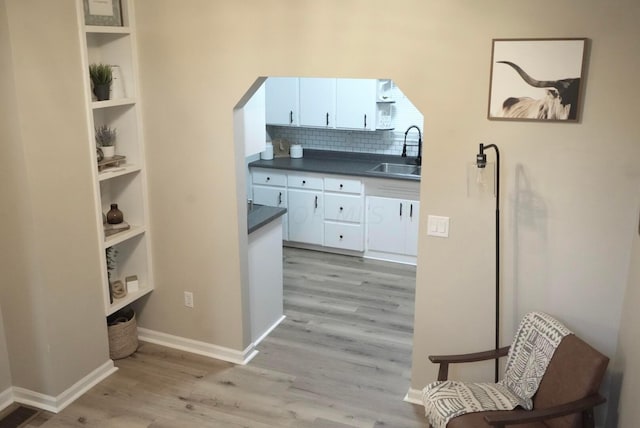 kitchen featuring backsplash, light hardwood / wood-style flooring, white cabinetry, and sink