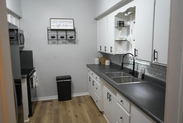 kitchen with black electric range oven, sink, light hardwood / wood-style flooring, tasteful backsplash, and white cabinetry