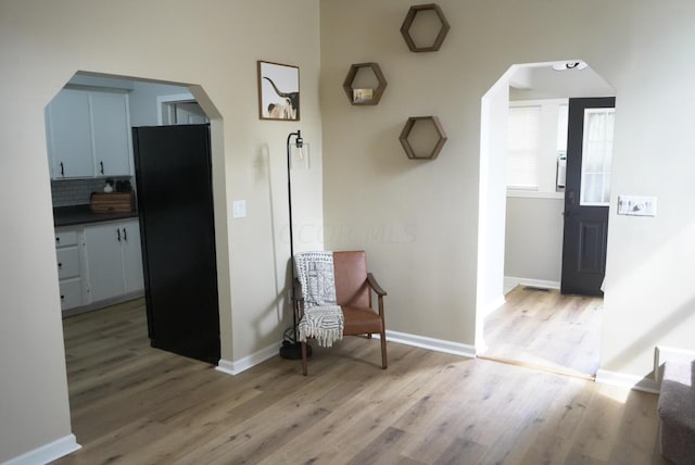 kitchen featuring black refrigerator, backsplash, and light hardwood / wood-style floors