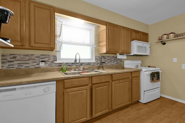 kitchen with backsplash, white appliances, sink, and light hardwood / wood-style flooring