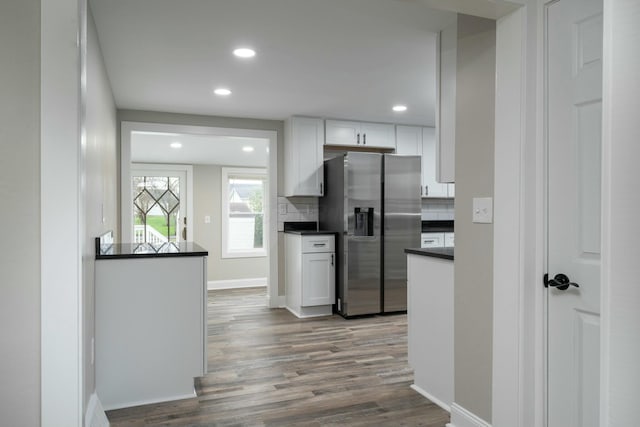 kitchen featuring decorative backsplash, stainless steel fridge, light wood-type flooring, and white cabinetry