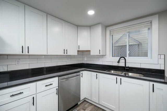 kitchen featuring dishwasher, white cabinetry, dark stone counters, and sink