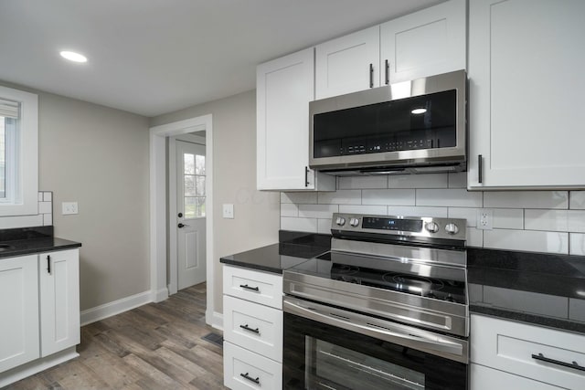 kitchen with white cabinets, appliances with stainless steel finishes, dark hardwood / wood-style floors, and tasteful backsplash