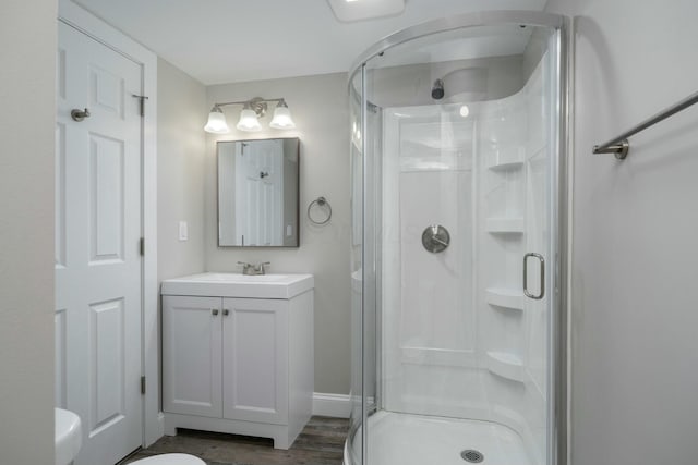 bathroom with vanity, toilet, an enclosed shower, and wood-type flooring