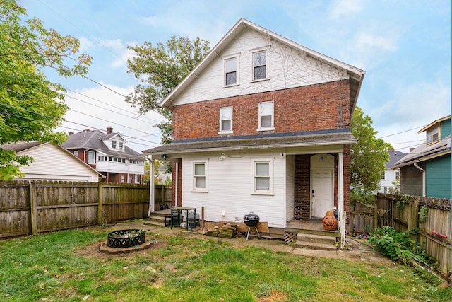 rear view of house featuring a lawn and a fire pit