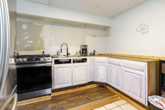 kitchen featuring sink, a drop ceiling, stainless steel appliances, tile patterned floors, and white cabinets