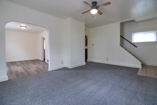 unfurnished living room with dark colored carpet, ceiling fan, and ornamental molding