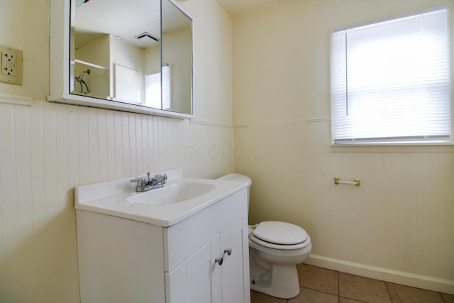 bathroom with tile patterned floors, a wealth of natural light, vanity, and toilet