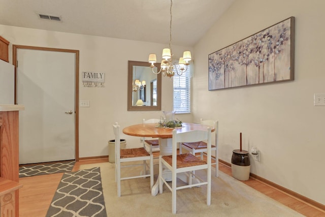 dining room featuring a chandelier, vaulted ceiling, and wood-type flooring