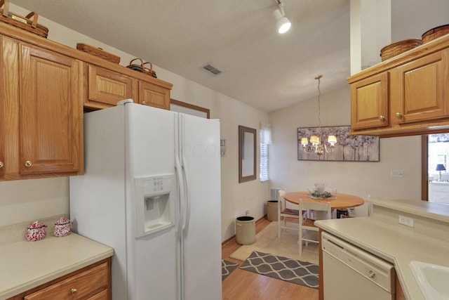 kitchen featuring light hardwood / wood-style flooring, a notable chandelier, pendant lighting, vaulted ceiling, and white appliances