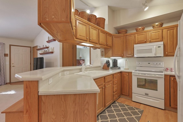 kitchen featuring sink, kitchen peninsula, track lighting, white appliances, and light wood-type flooring