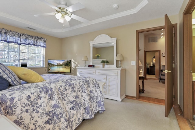 carpeted bedroom featuring a tray ceiling, ceiling fan, and crown molding